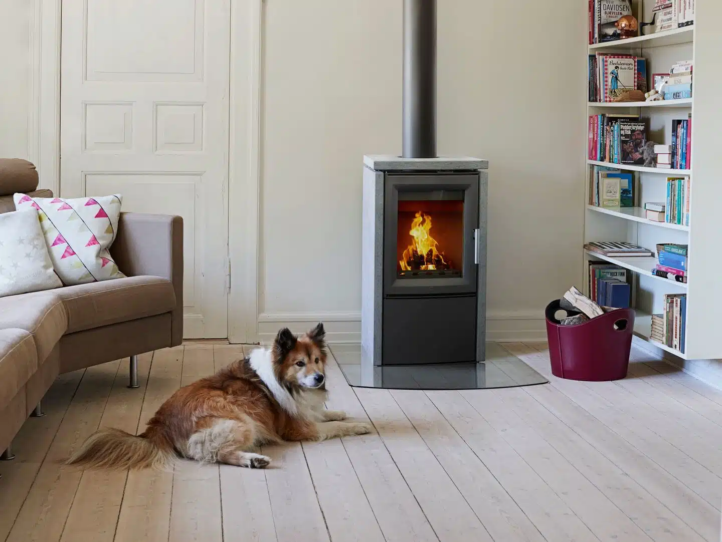 eleganter kamin varde aura 3 mit naturstein im gemütlichen wohnzimmer mit einem hund